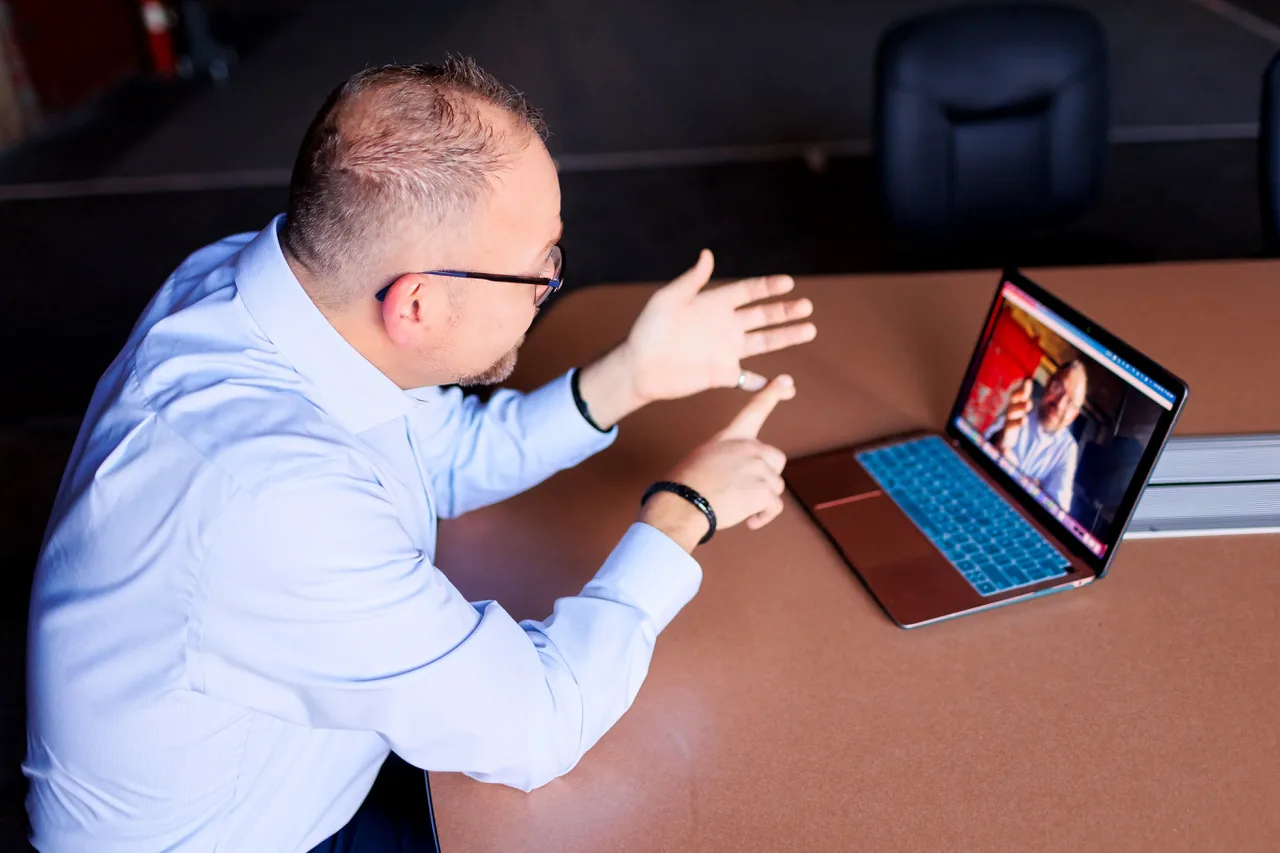 Noah Kaye mid-conversation on a video call, gesturing with both hands