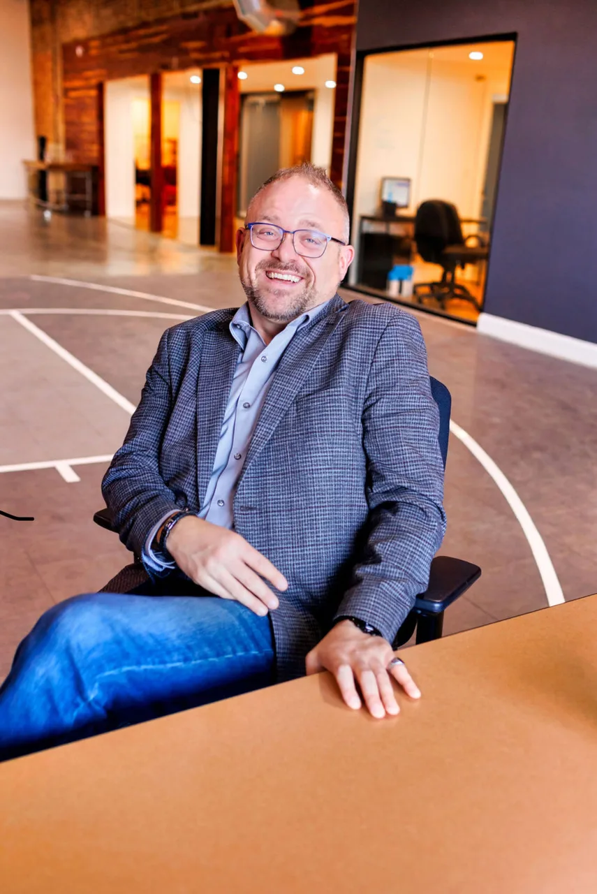 Noah Kaye laughing, seated at a table in a loft office