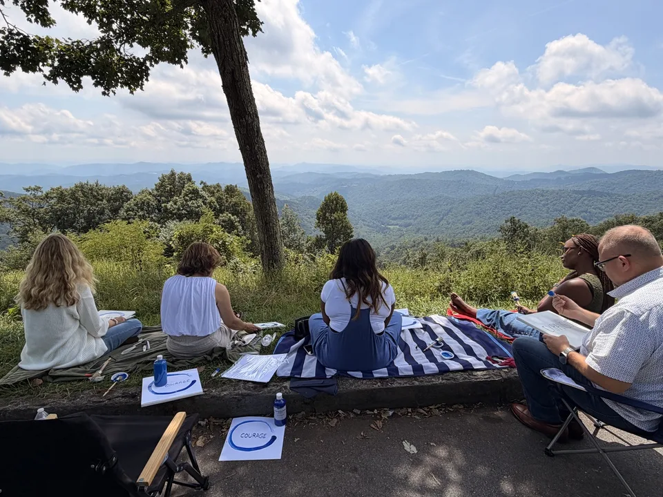 Noah Kaye and a small group painting at a mountain overlook during a retreat