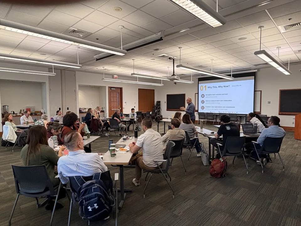 Noah Kaye presenting to a room of leaders seated around tables